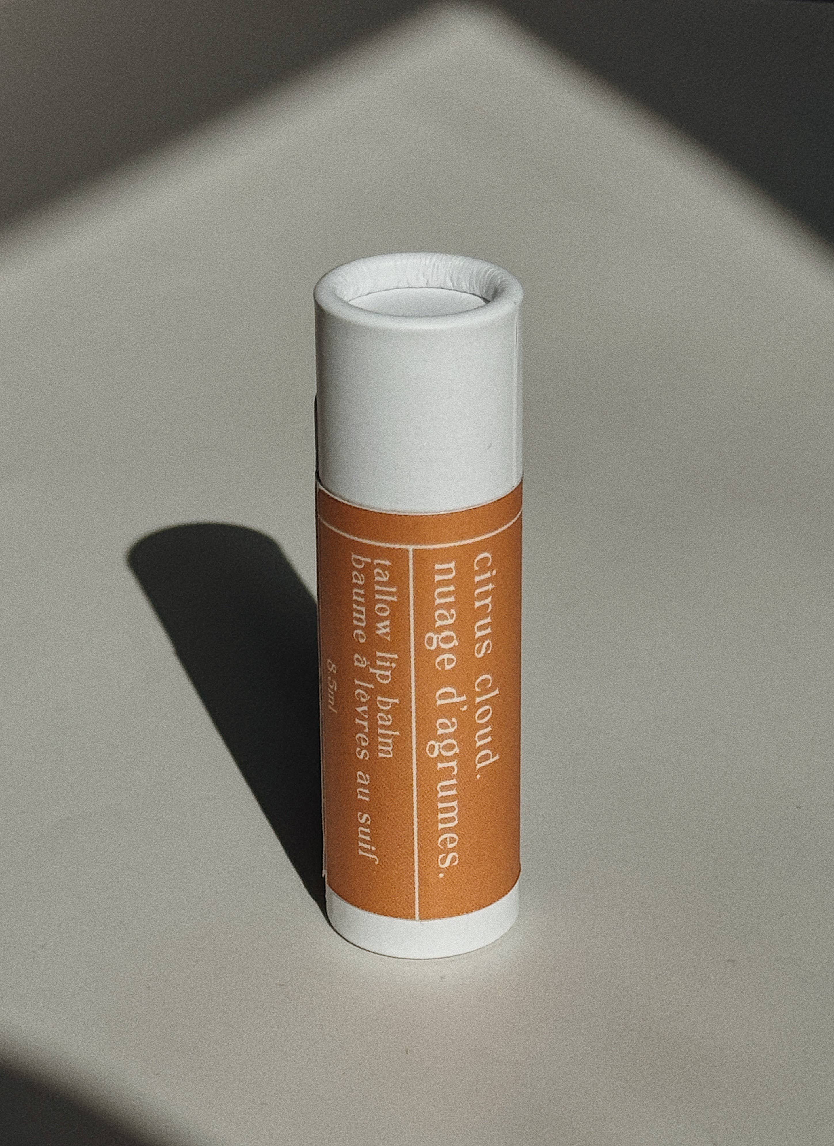 Genesis Tallow Lip balm with a white cap and brown label on a light gray background