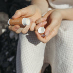 Genesis Tallow lip balm held by hands against a blurred background