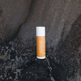 Genesis Tallow Lip balm tube on a textured black surface