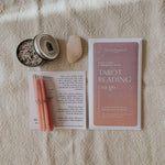Homebound Tarot reading kit with cards, candles, and a stone on a textured surface