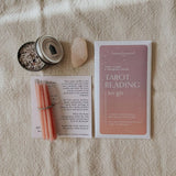Homebound Tarot reading kit with cards, candles, and a stone on a textured surface