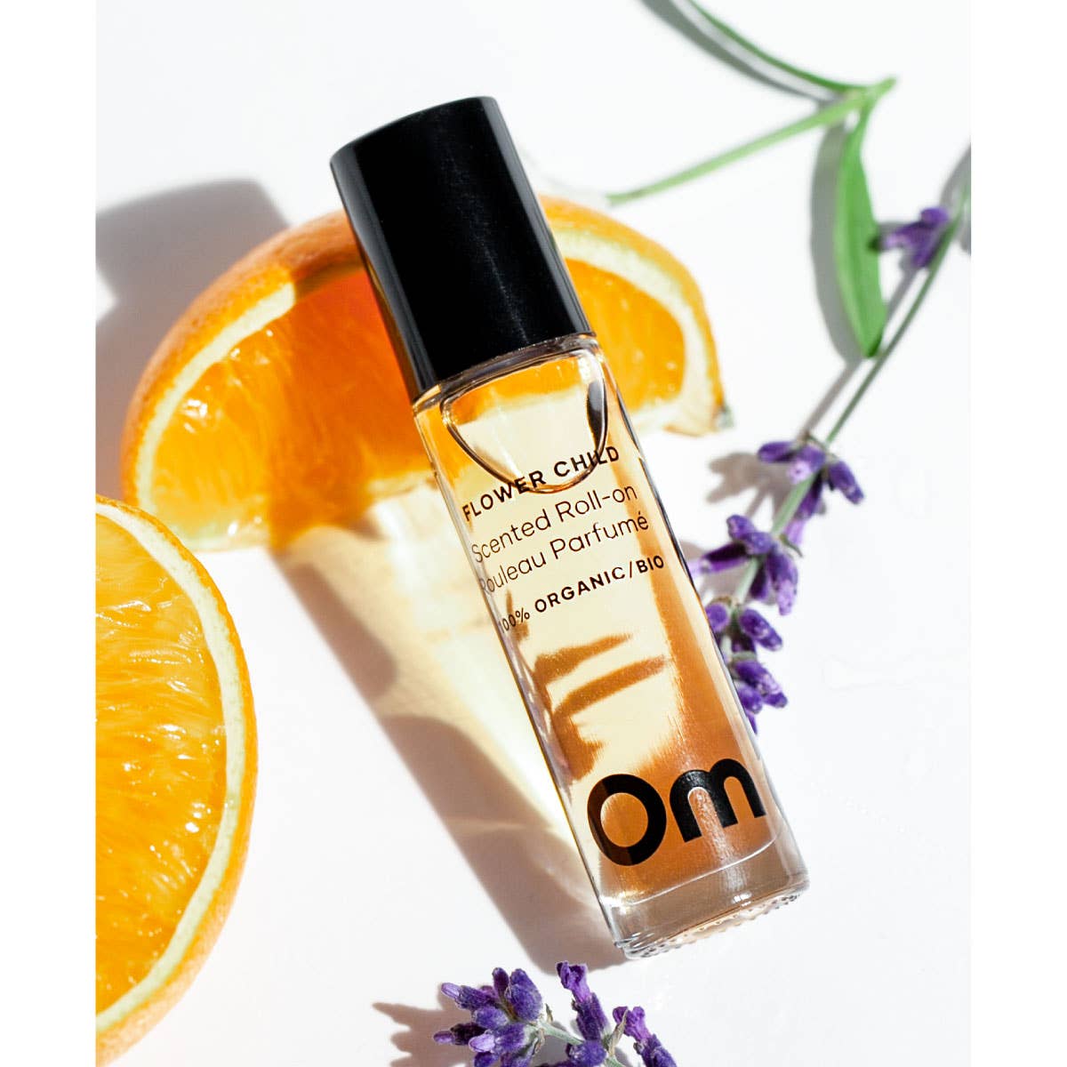 Om Organics Roll-on perfume bottle with oranges and lavender on a white background