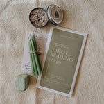Tarot cards, candles, and a stone on a textured surface
