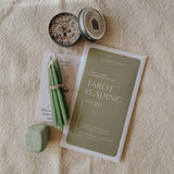 Tarot cards, candles, and a stone on a textured surface