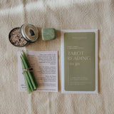 Tarot reading kit with tarot cards, candles, and a crystal on textured surface