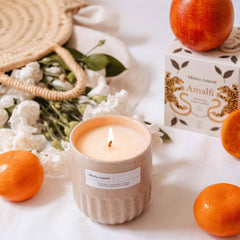 Mimi and August Candle with a label, oranges, and a box on a white surface