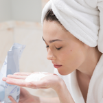 Woman smelling The Bathologist salts wearing a towel on her head.