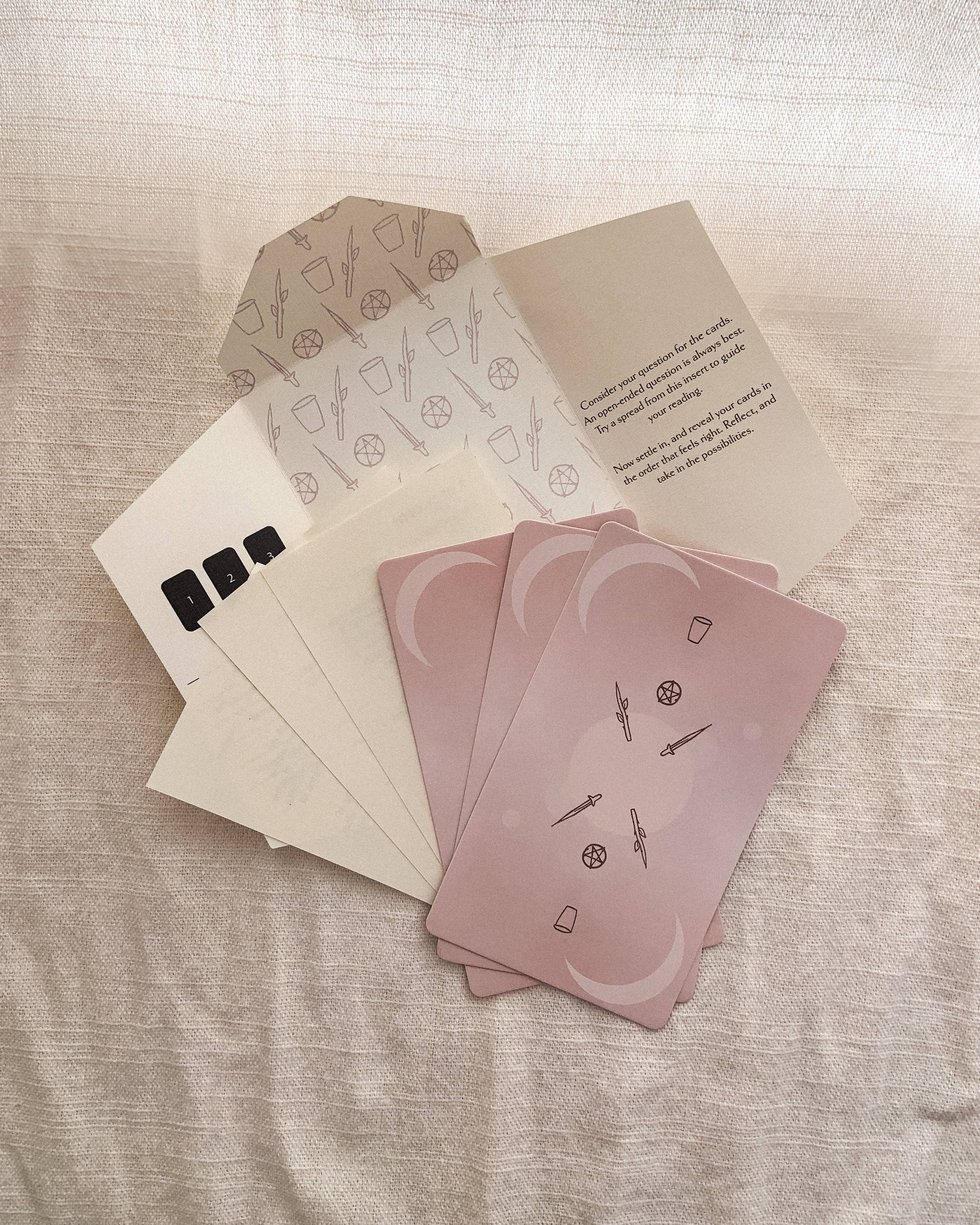 Set of pink Homebound Tarot cards with icons on a textured surface