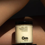 Jar of Om Organics body scrub on a person's skin