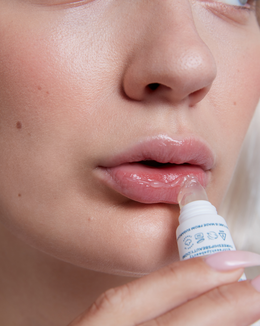Person applying Three Ships Soft Serve lip balm to their lips with a close-up focus on the action.