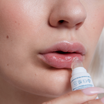 Person applying Three Ships Soft Serve lip balm to their lips with a close-up focus on the action.
