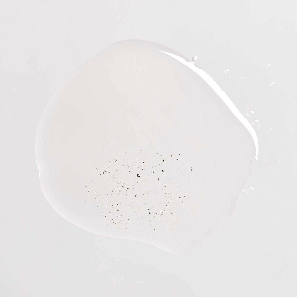 Om Organics body oil Clear oil-like substance with small particulates on a light gray background