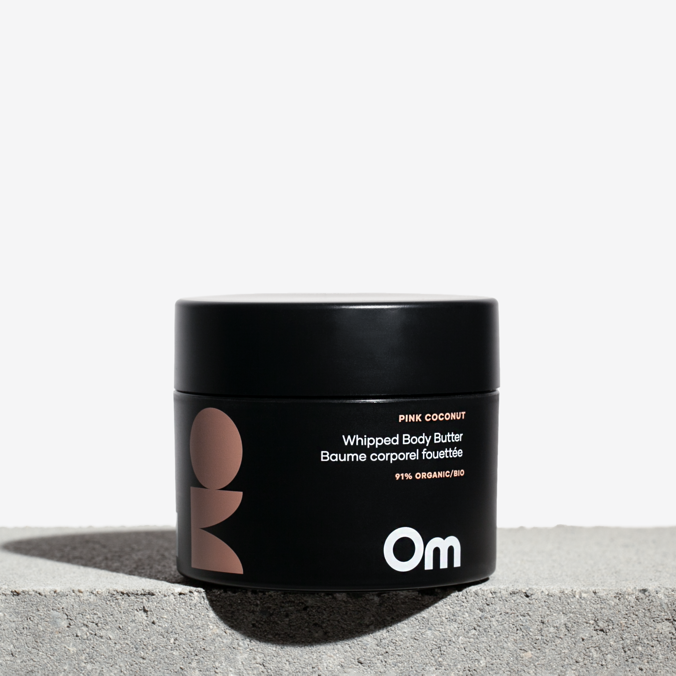 Black jar of Om Organics body butter on a light background