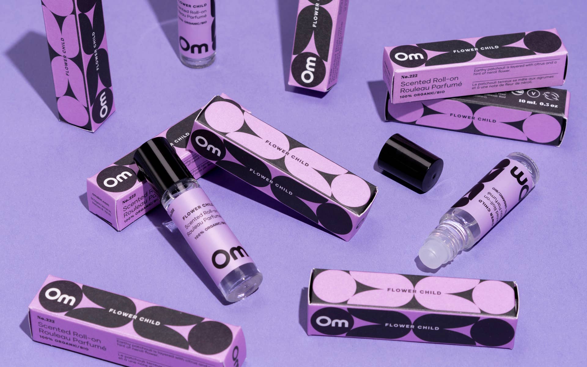 Om perfume products including bottles and boxes on a purple background