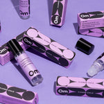 Om perfume products including bottles and boxes on a purple background