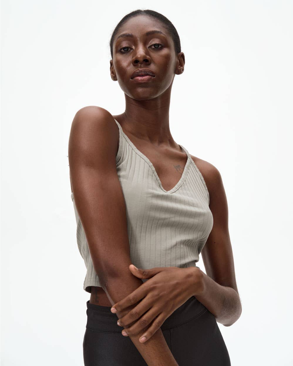 Woman wearing a beige sleeveless top against a white background