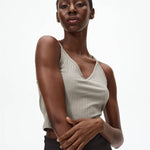 Woman wearing a beige sleeveless top against a white background