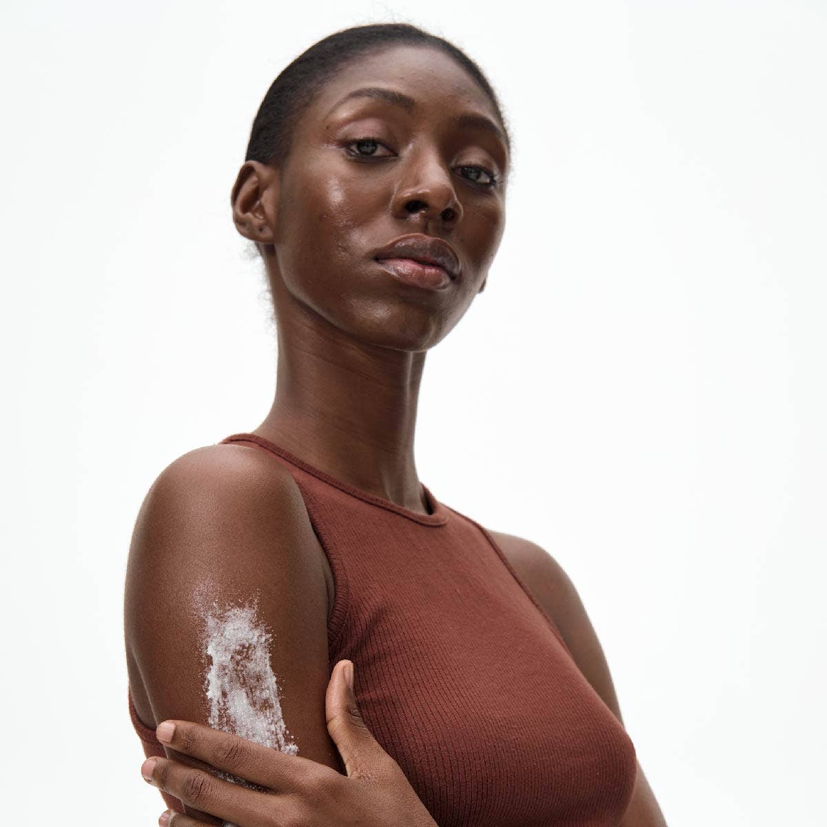 Woman with a visible body scrub on her arm against a white background