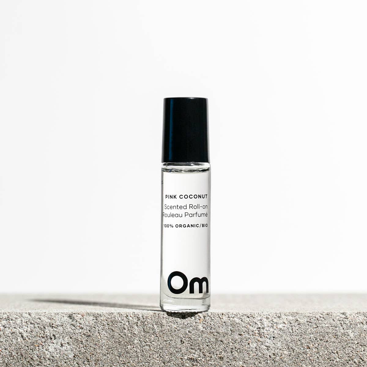 Roll-on perfume bottle labeled 'Pink Coconut' by Om Organic Skincare on a light background