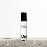 Roll-on perfume bottle labeled 'Pink Coconut' by Om Organic Skincare on a light background