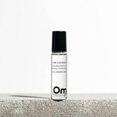 Roll-on perfume bottle labeled 'Pink Coconut' by Om Organic Skincare on a light background