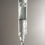 Glass dropper with a drop of Graydon Supermoon serum on a gray background