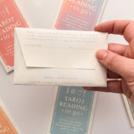 Hand holding a Homebound tarot card envelope with tarot cards in the background