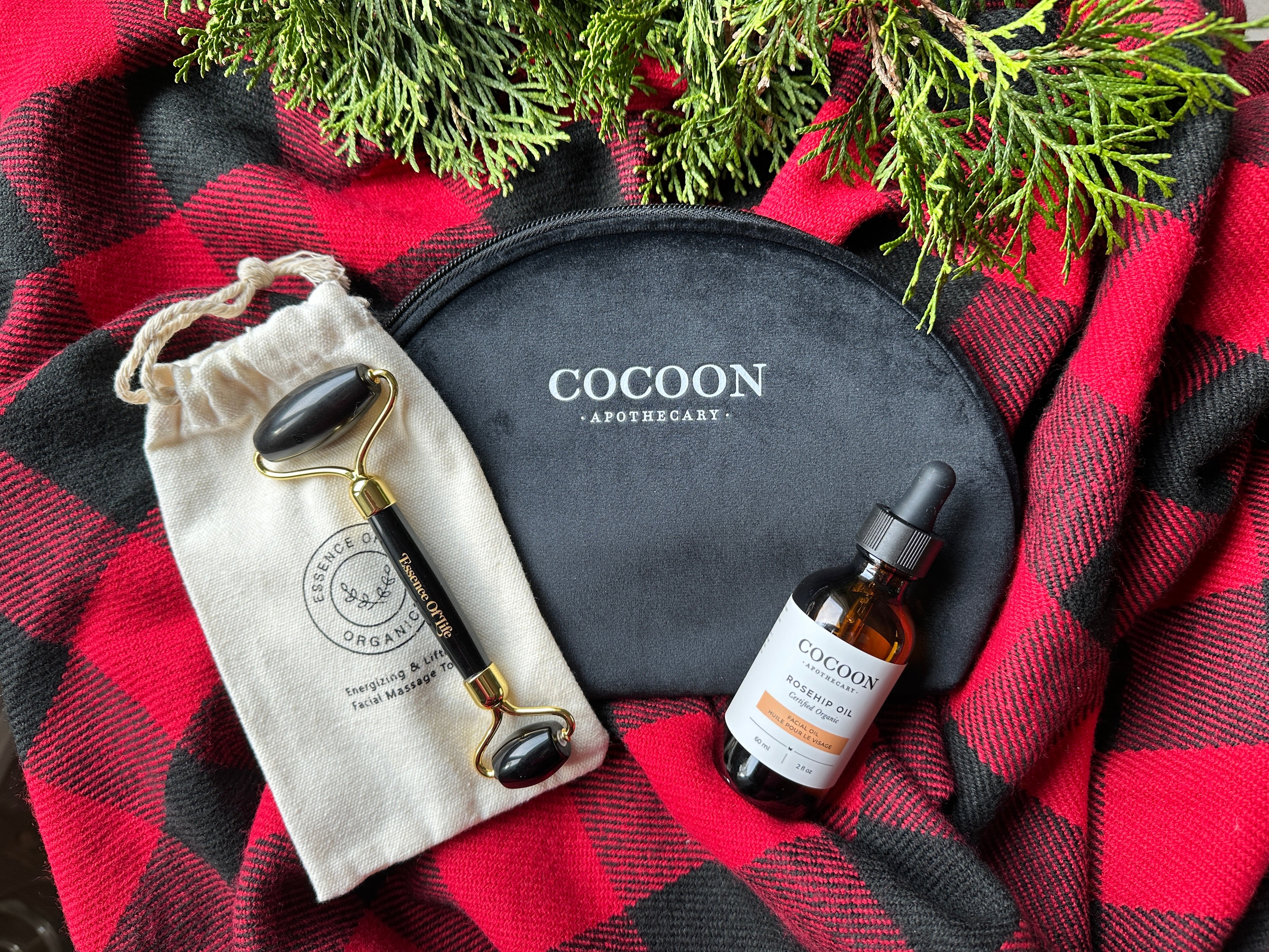 Cocoon Apothecary skincare products on a red and black checkered fabric with greenery.