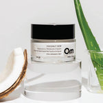 Om Organics Coconut Dew cream with a coconut and aloe vera leaf on a light background. 