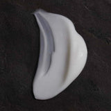 OM Organics Coconut Dew Cream White cream texture on a dark textured background.