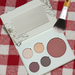 Pure Anada Makeup palette with four colors and a brush on a red and white checkered tablecloth