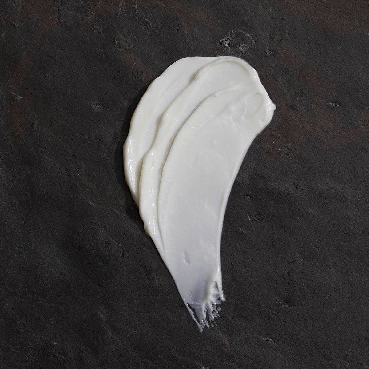 Om Organics body butter smear on a dark textured surface