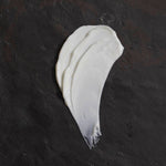 Om Organics body butter smear on a dark textured surface