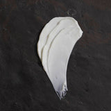 Om Organics body butter smear on a dark textured surface