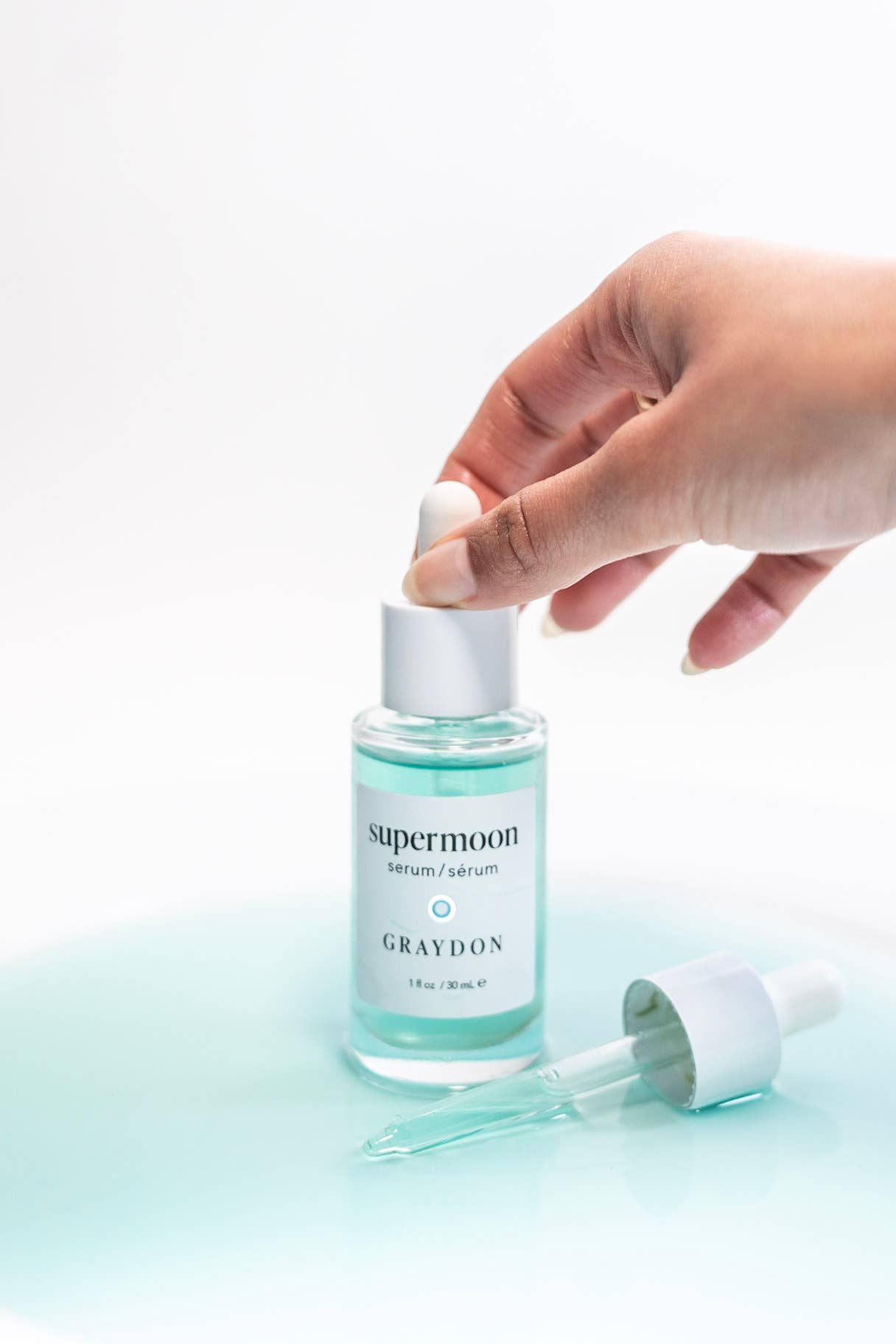 Hand holding a bottle of 'supermoon' serum by Graydon 