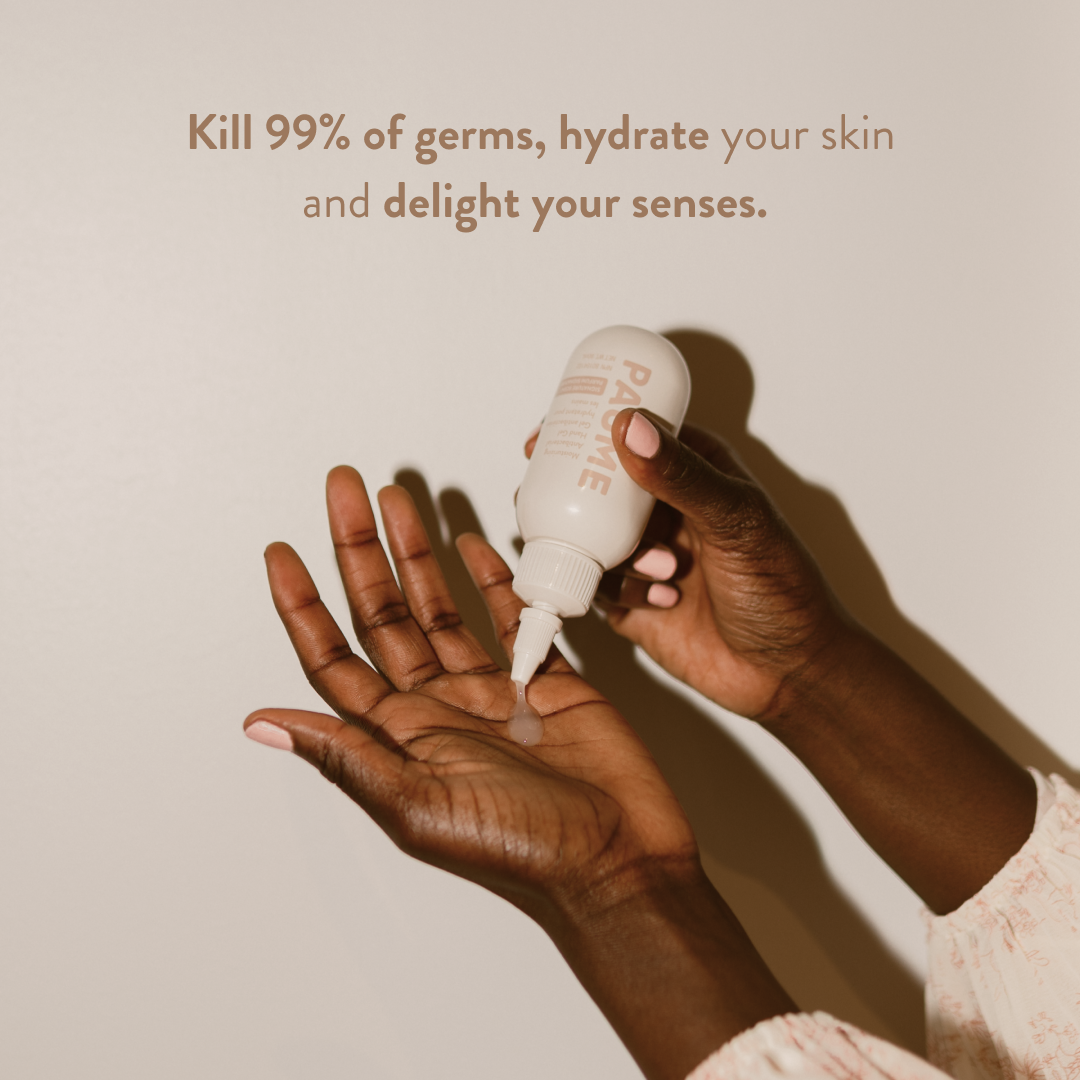 Hand holding a bottle of Paume antibacterial hand gel with text on a plain background.
