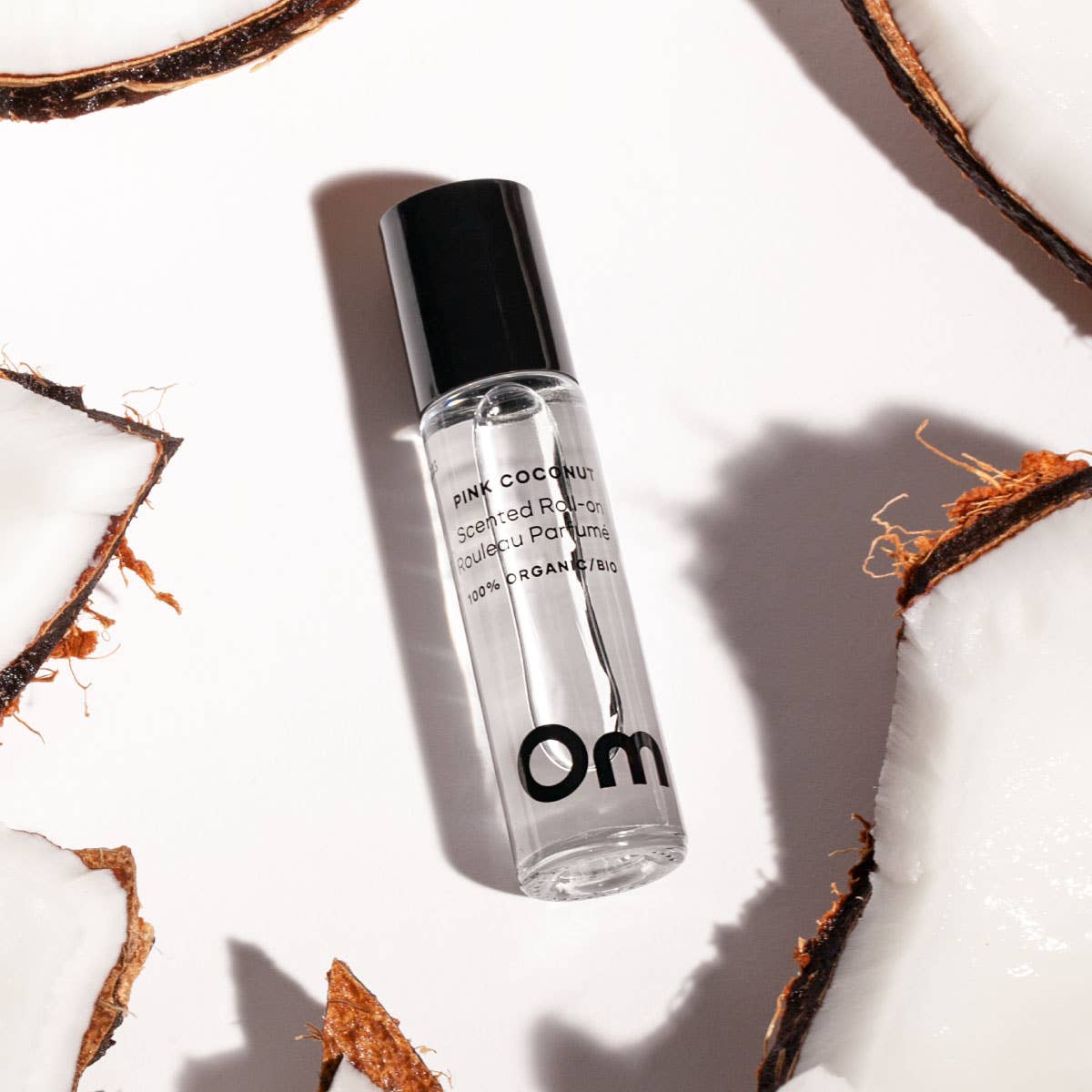 Om Roll-on perfume bottle labeled 'om' on a white background with coconut pieces.