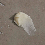 Om Organics body scrub swatch on sandy background