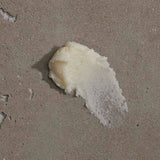 Om Organics body scrub swatch on sandy background