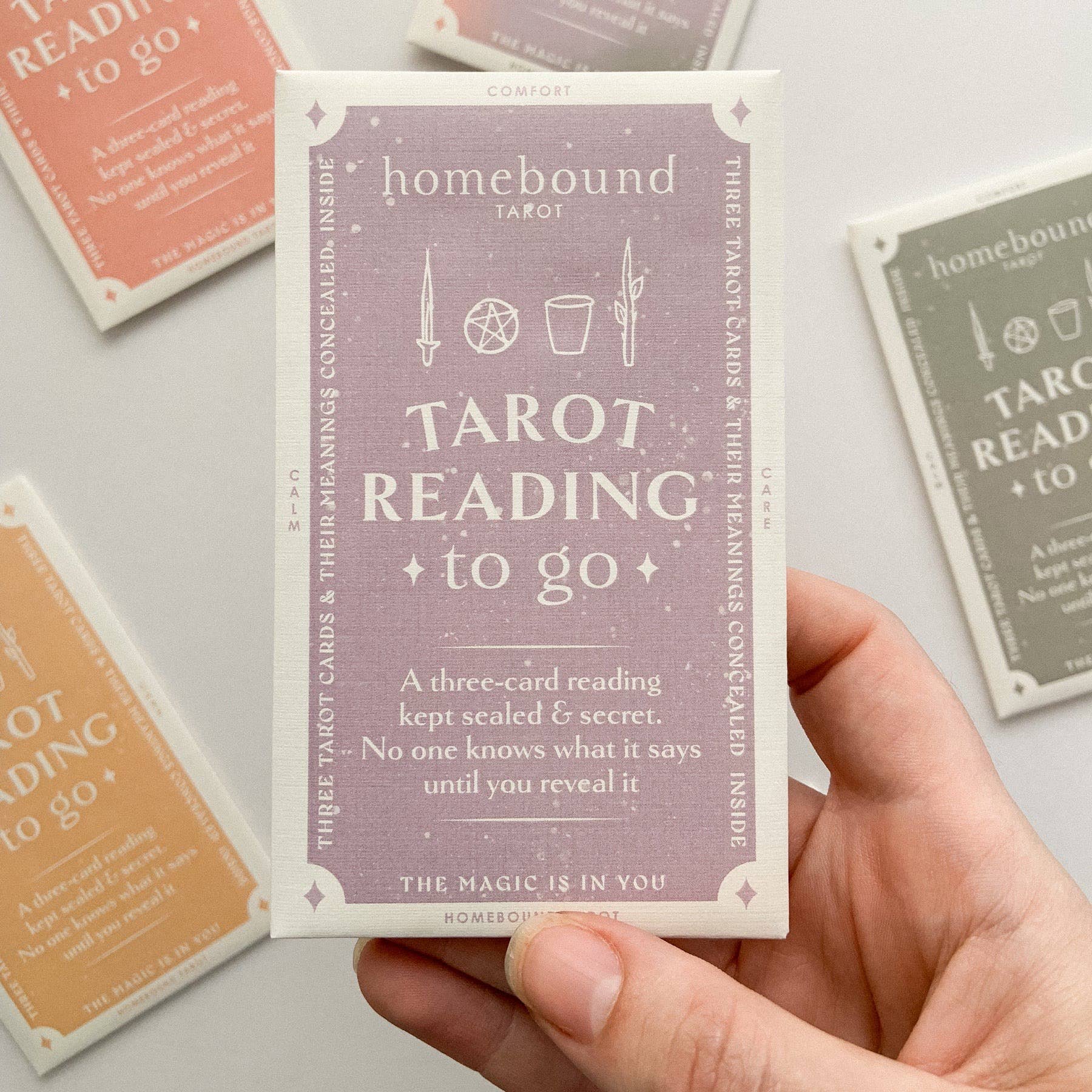 Hand holding a tarot card from Homebound tarot on a light background.