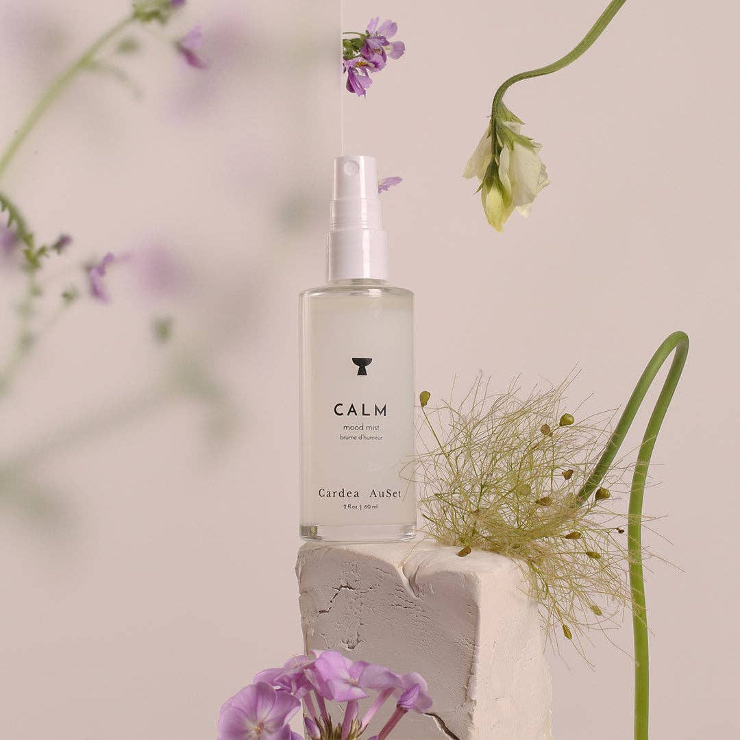 Cardea AuSet mood spray bottle in Calm surrounded by flowers on a light background