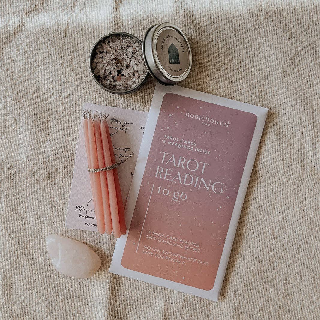 Homebound Tarot reading kit with candles, stones, and tarot cards on a textured surface